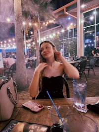 a woman sitting at a table with a drink